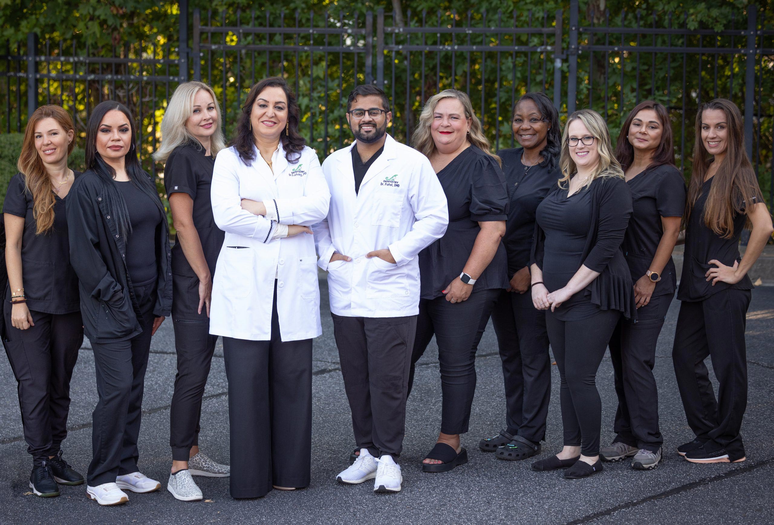 A group of people posing together outdoors, with some individuals wearing scrubs and stethoscopes, suggesting they are healthcare professionals.