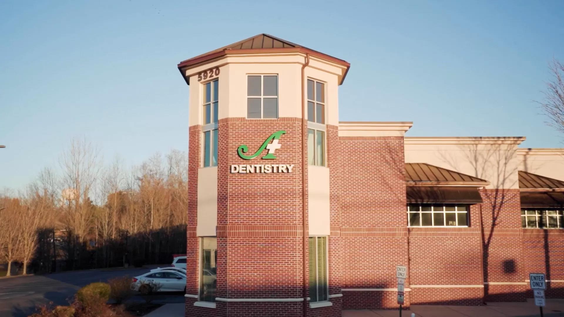 The image shows a building with a sign that reads 'dentistry' on its facade, indicating it's a dental practice, set against a clear sky during daylight hours.