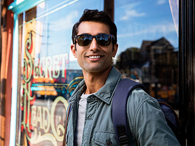 A man with sunglasses stands outside a shop window.