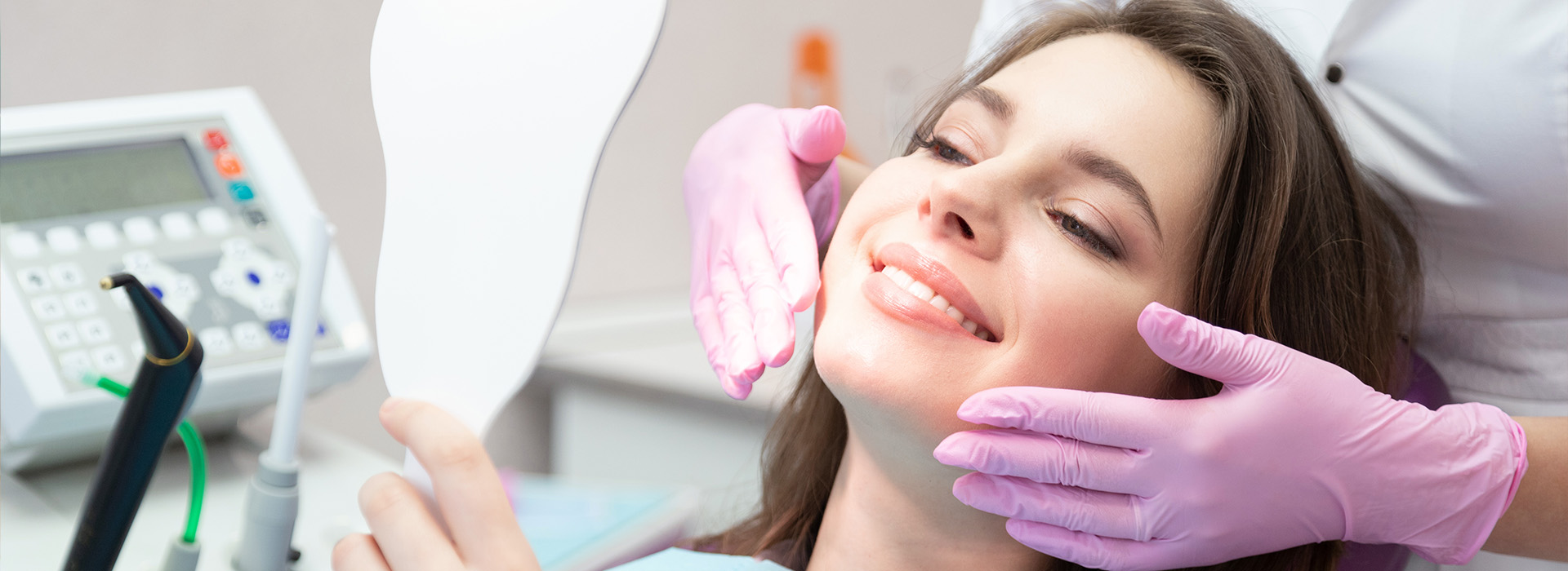 The image shows a woman sitting in a dental chair with her eyes closed, receiving dental care from a professional wearing purple gloves and a white mask.