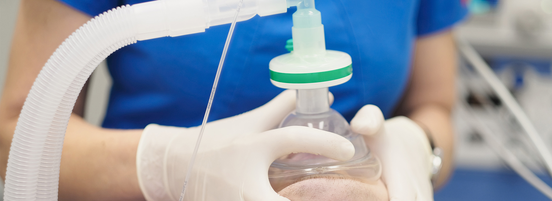 The image depicts a medical setting with a person wearing gloves and a mask, holding a clear plastic bag filled with a yellowish-green liquid, possibly related to medical treatment or procedure.