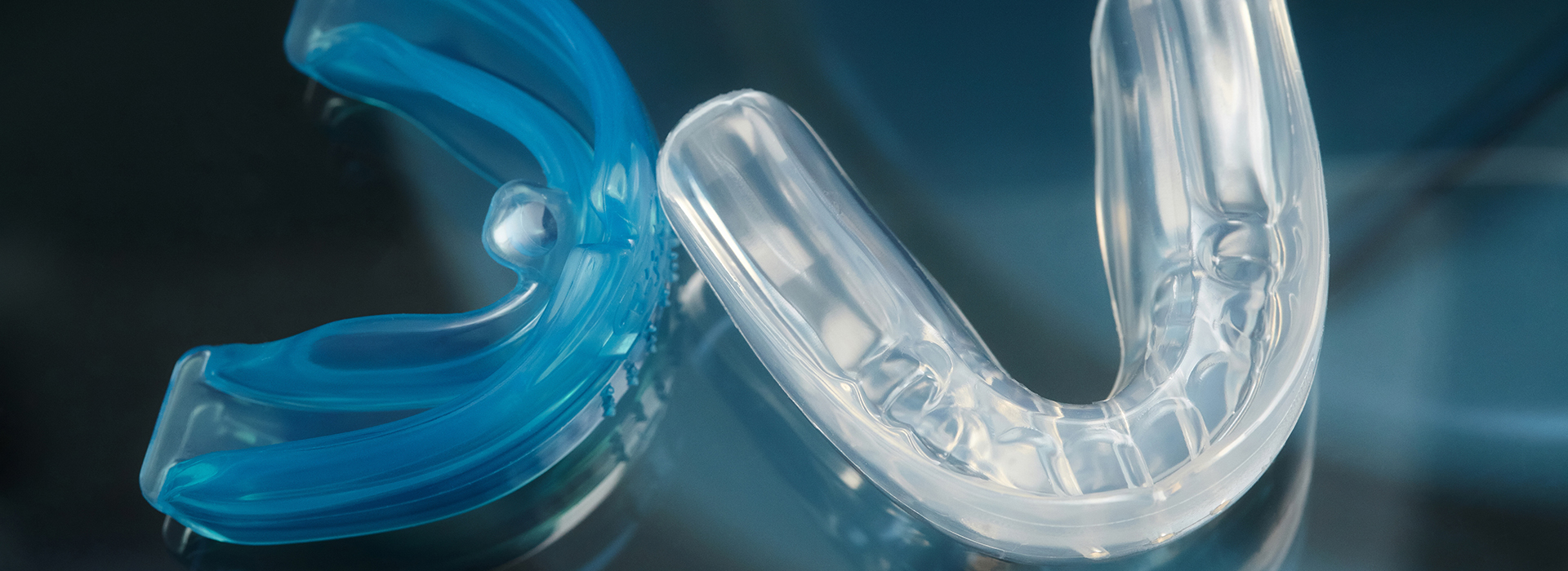 The image features a close-up view of a blue and clear plastic object with a shiny surface, possibly a piece of plastic with a reflective quality, against a dark background.
