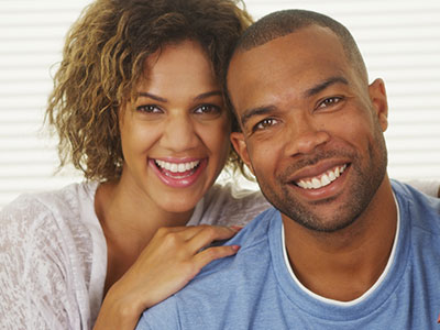 The image shows a man and a woman posing together with smiles, sharing an intimate moment.