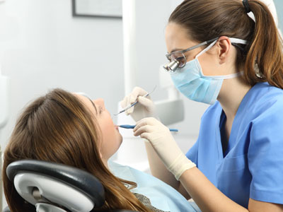 The image depicts a dental professional assisting a patient with an oral procedure, likely in a dental office setting.