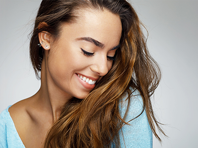 The image features a young woman with long hair smiling and looking down at her shoulder, wearing a light blue top, with two different versions of the same photo side by side.