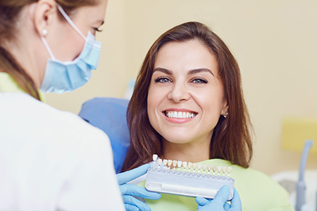 A woman receiving dental care from a professional, with both individuals wearing face masks.