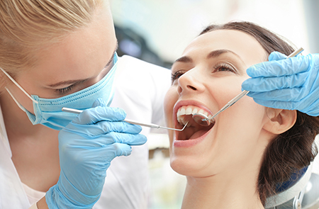 The image depicts a dental hygiene professional performing oral care on a patient s teeth using specialized equipment.