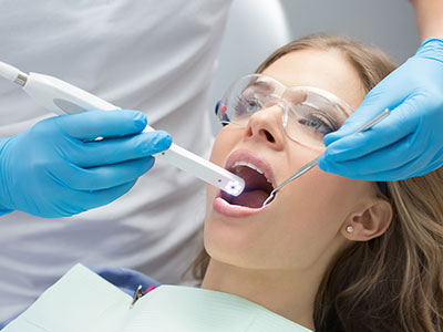 The image depicts a dental professional performing oral care on a patient using specialized equipment.