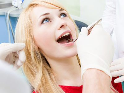 Woman receiving dental care with dentist performing procedure.
