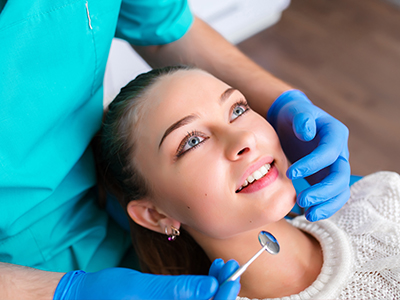 A woman receiving dental treatment with a dentist attending to her.