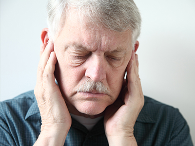The image shows two side-by-side photographs of an older man with his hands on his face, possibly in a state of distress or concern, with one photo being in color and the other in black and white.
