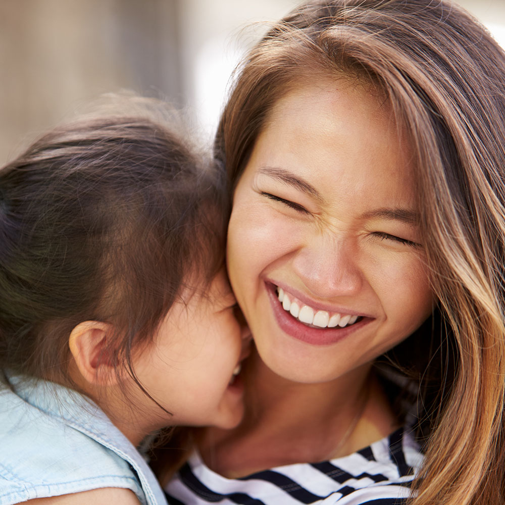 A woman with a child is smiling at the camera, creating a warm, familial atmosphere.